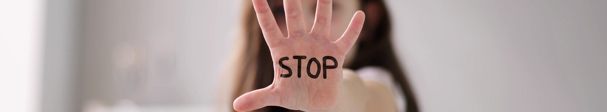 Ein Mädchen streckt zur Abwehr die Hand nach vorne. Darauf geschrieben steht das Wort "stop".