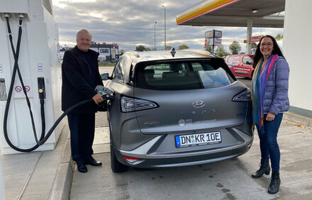 Bild zeigt Landrat Wolfgang Spelthahn und Anne Schüssler neben einem Wasserstoff-Auto.