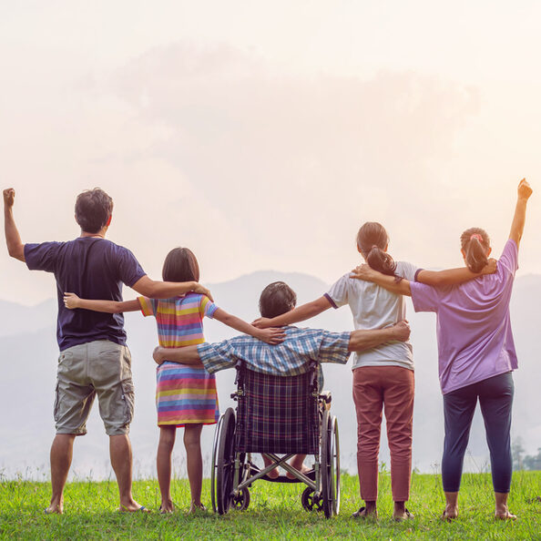 Rückansicht einer Familiengruppe mit einem Mann im Rollstuhl