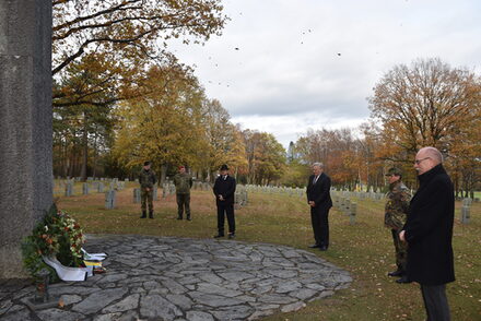 Soldaten und Vertreter der Kreisverwaltung Düren stehen vor einem Kranz an der Gedenkstätte in Hürtgenwald.