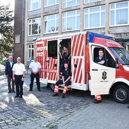 Die Vertreter des Kreises stehen vor dem Kreishaus am Rettungswagen und begrüßen die neuen Azubis.