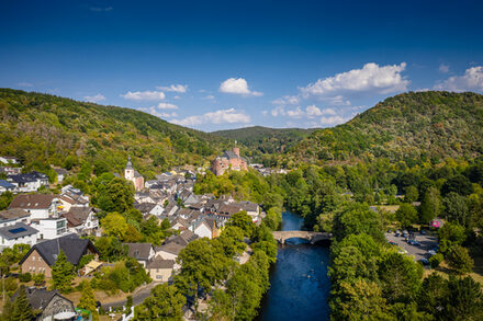 Die Stadt Heimbach von oben. Zu sehen ist viel Grün, Wasser und einige Häuser