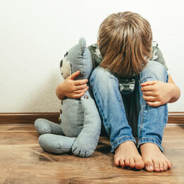 Trauriger Junge mit Teddy in der Hand