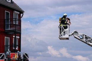 Bei einer Feuerwehrübung wird eine Frau aus einem Haus gerettet.