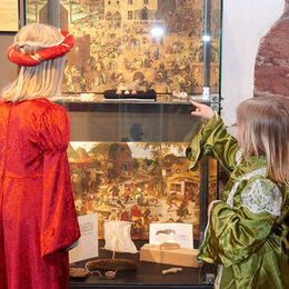 Zwei Kinder stehen in mittelalterlicher Kleidung im Burgenmuseum