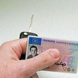Ein Mann hält einen Führerschein in der Hand.