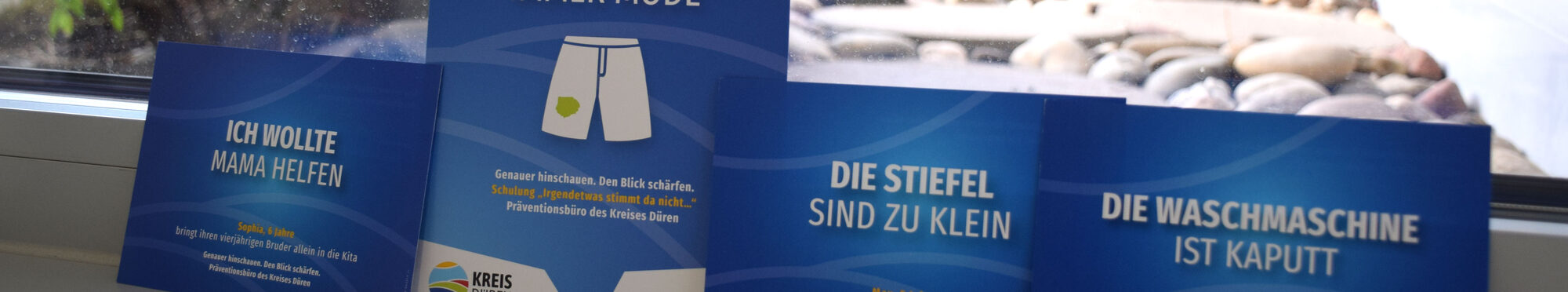 Vier Postkarten lehnen an einer Fensterscheibe. Sie machen auf die Initiative "Gut aufwachsen" aufmerksam.