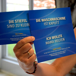 Eine Frau hält drei Postkarten fest, die auf die Initiative "Gut aufwachsen im Kreis Düren" aufmerksam macht