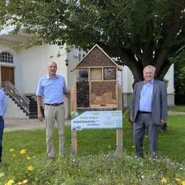 Eric Floren, Bürgermeister Dr. Timo Czech und Landrat Wolfgang Spelthahn stehen vor dem großen Insektenhotel am Nörvenicher Rathaus.