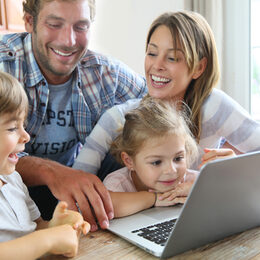 Parents with kids at home using laptop computer