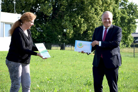 Landrat Wolfgang Spelthahn steht neben Marianne Mielke, die die Kita leitet, und nimmt die Zertifikate entgegen