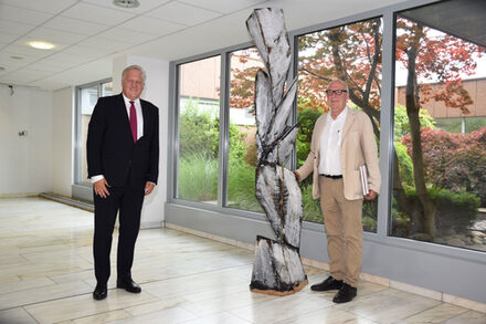 Landrat Wolfgang Spelthahn und Künster Karl Manfred Rennertz stehen vor seinem Werk, das im Kreishaus ausgestellt ist.