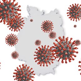 Coronaviren schwirren vor einem Deutschlandumriss