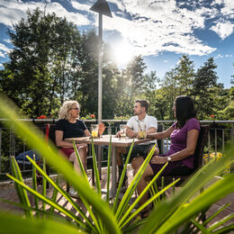 Menschen sitzen auf einer Terrasse und trinken etwas.