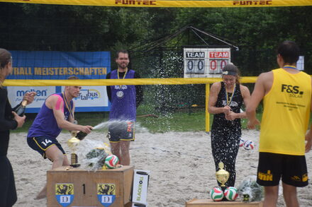 Die Sieger des Beach-Cup feiern mit einer Champagner-Dusche.
