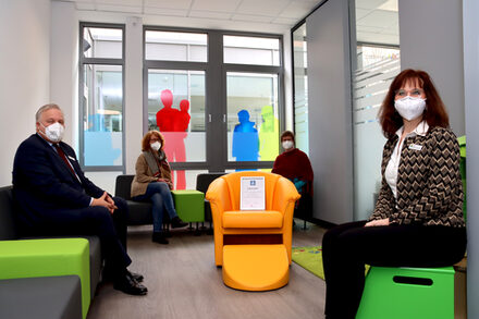 Vier Personen im neuen Familienbüro des Kreises Düren. Zu sehen sind bunte Stühle, alle Personen sitzen.