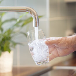 Filling up a glass with clean drinking water from kitchen faucet