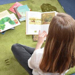 Eine Frau sitzt auf dem Boden und liest ein Buch.