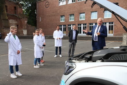 Landrat Wolfgang Spelthahn und Schülerinnen und Schüler vor einem Wasserstoff-Auto.