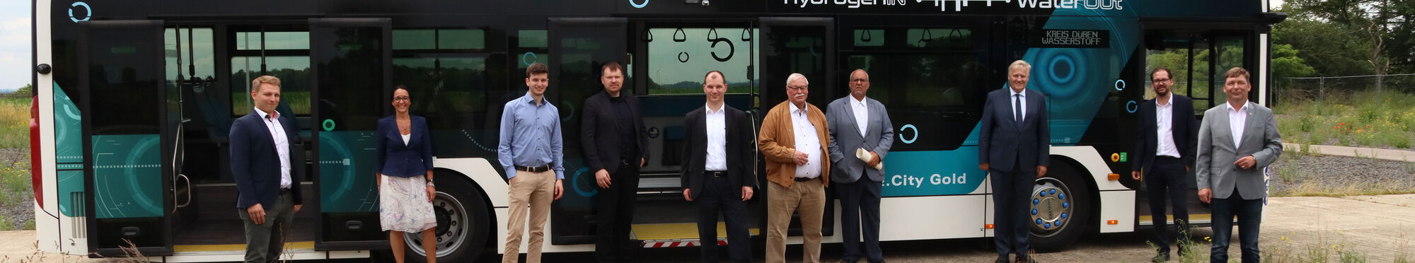 Eine Gruppe von Menschen steht vor dem Wasserstoff-Bus.