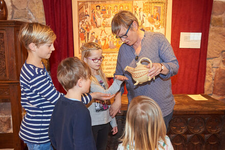 Eine Frau zeigt Kindern eine Kanne