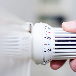 Close Up Of Hand Adjusting Heating Thermostat.