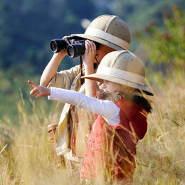 Children brother and sister playing outdoors pretending to be on safari and having fun together with binoculars and hats