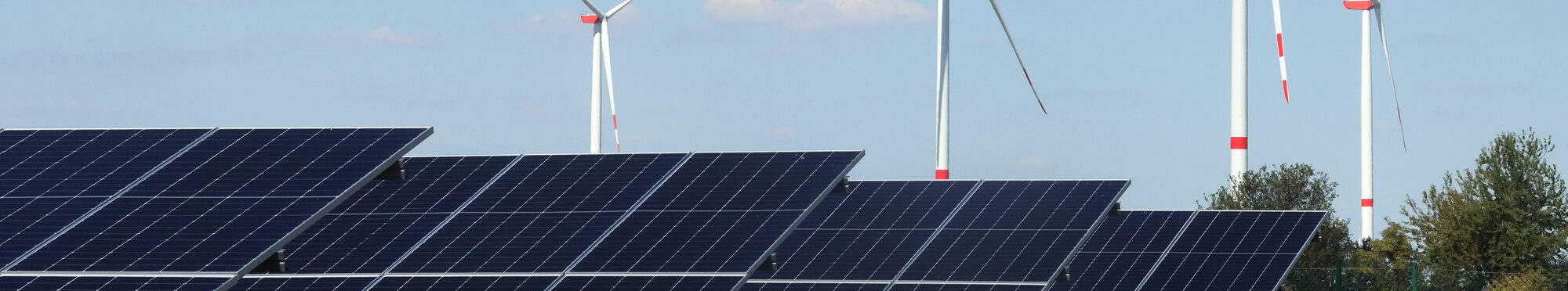 Das Foto zeigt große Solarplatten und Wundräder im Hintergrund