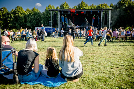 Familien auf der Wiese lauschen der Musik auf der Bühne