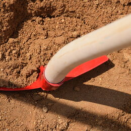 Eine rote Schaufel im Sand.