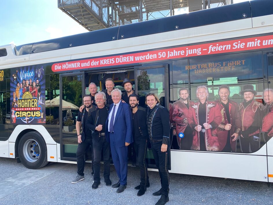 Höhner und Landrat vor dem beklebten Bus.