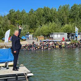 Die Teilnehmer des Indeland-Triathlons im Wasser. Landrat Wolfgang Spelthahn steht vorne links und gibt den Startschuss.