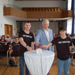 Landrat Wolfgang Spelthahn und zwei Jugendliche drücken den Knopf des Zufallgenerators.