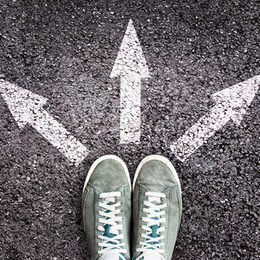 Shoes and arrows pointing in different directions on asphalt floor