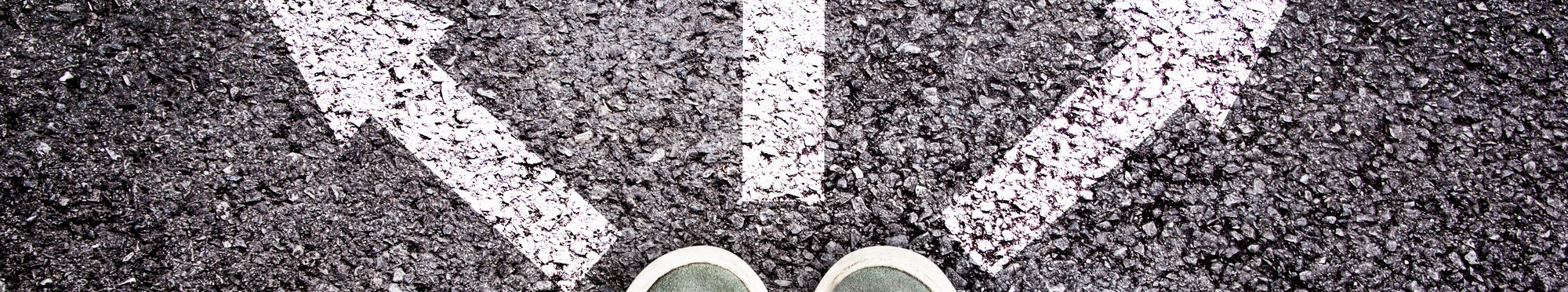 Shoes and arrows pointing in different directions on asphalt floor