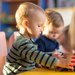 Preschool teacher and cute kids play in kindergarten