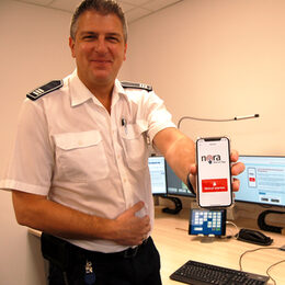Stefan Nepomuck, Leiter der Leitstelle des Kreises Düren, hält sein Smartphone mit der Nora-App in die Kamera.