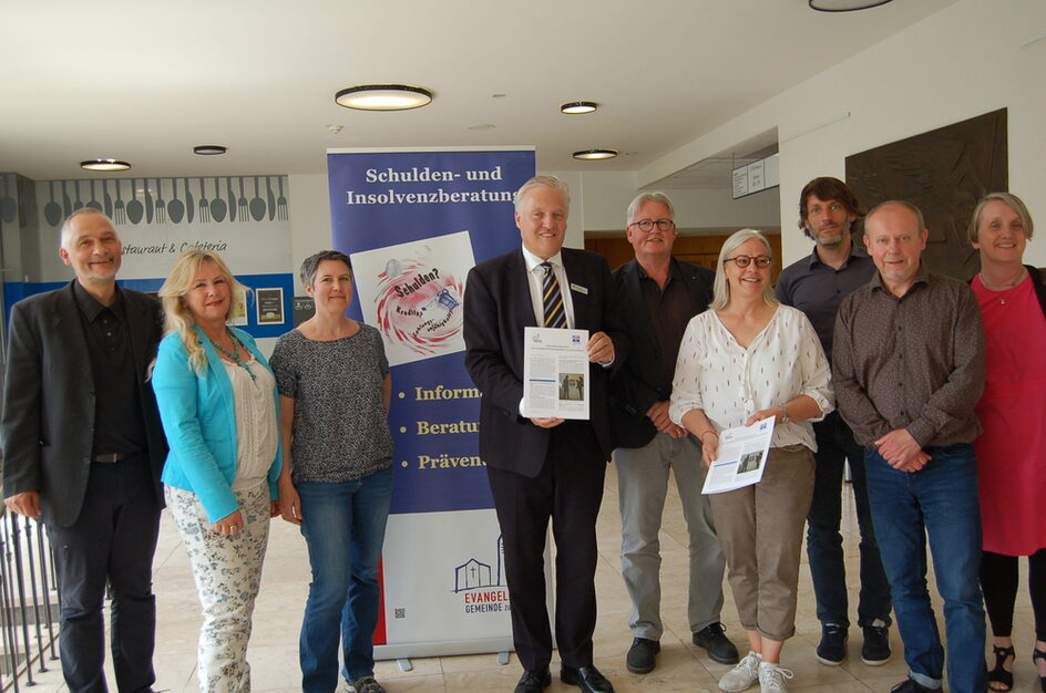 Neun Erwachsene präsentieren den Jahresbericht der Schuldnerberatung.