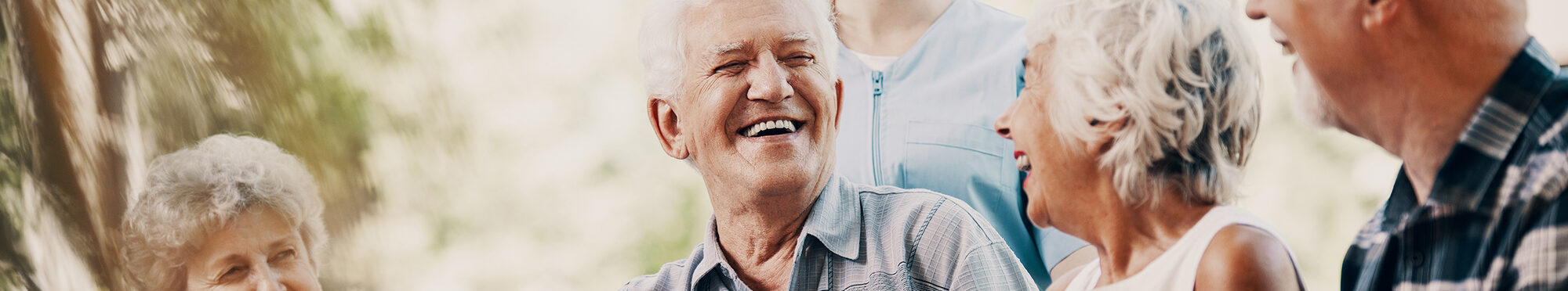 Happy elderly man with walking stick and smiling senior people relaxing in the garden