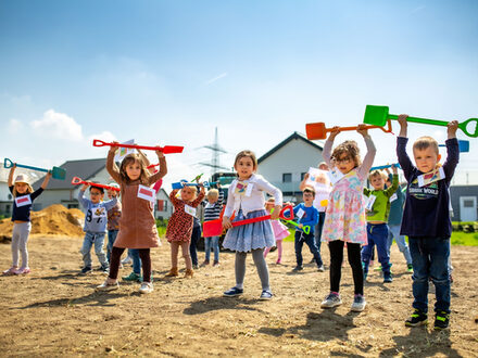 Tanzende Kinder mit Schaufeln.