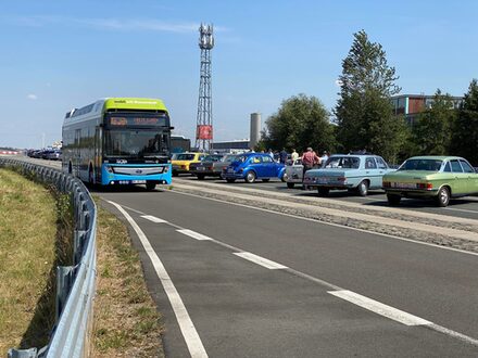 Wassertoffbus fährt an Oldtimern vorbei