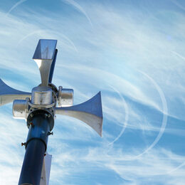 Outdoor loudspeaker against the background of blue sky, sound waves.