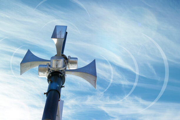 Outdoor loudspeaker against the background of blue sky, sound waves.