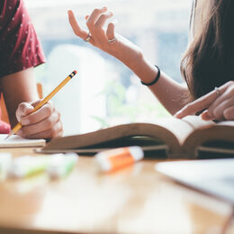 Young woman and man studying for a test or an exam. Tutor books with friends. Young students campus helps friend catching up and learning. People, learning, education and school concept.