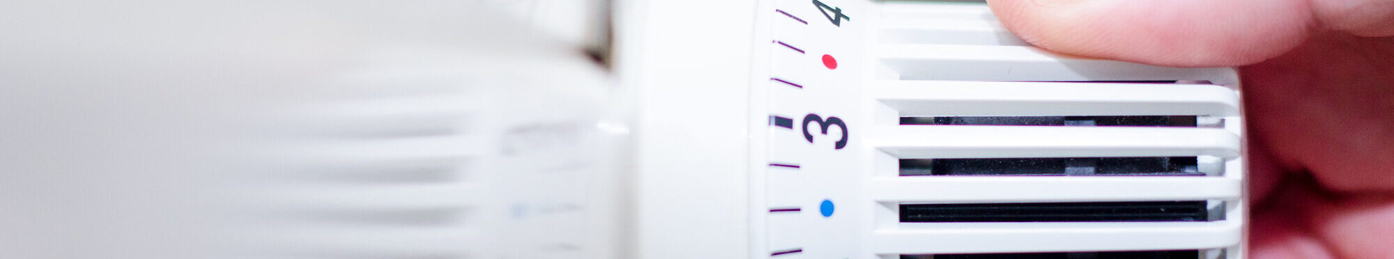 Close Up Of Hand Adjusting Heating Thermostat.