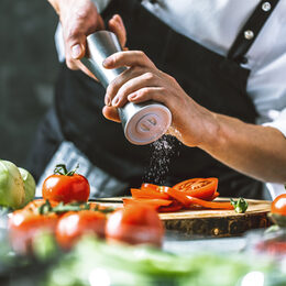 Koch würzt Tomaten in einer Küche