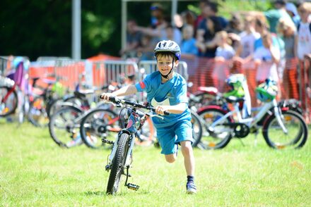 Ein Junge mit hält sein Fahrrad fest und läuft daneben.