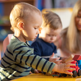 Preschool teacher and cute kids play in kindergarten