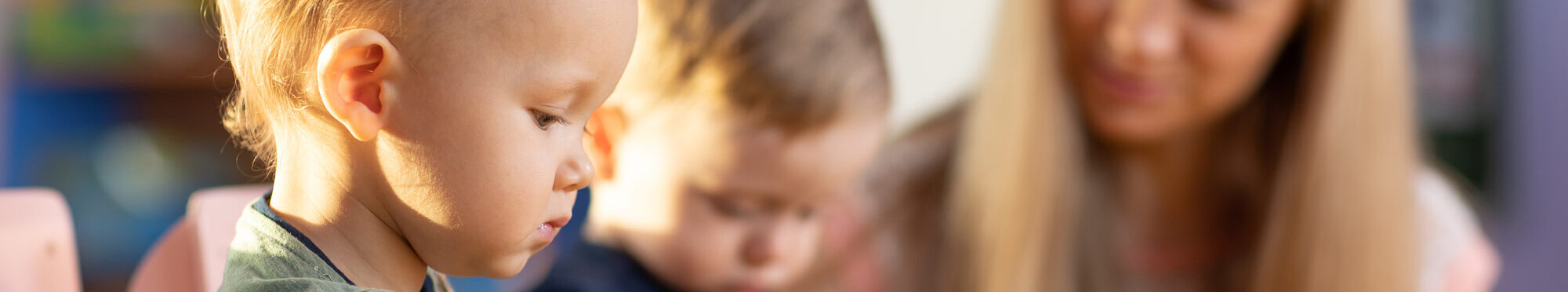 Preschool teacher and cute kids play in kindergarten