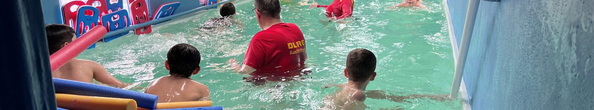 Das Bild zeigt ein kleines Schwimmbecken mit Menschen darin